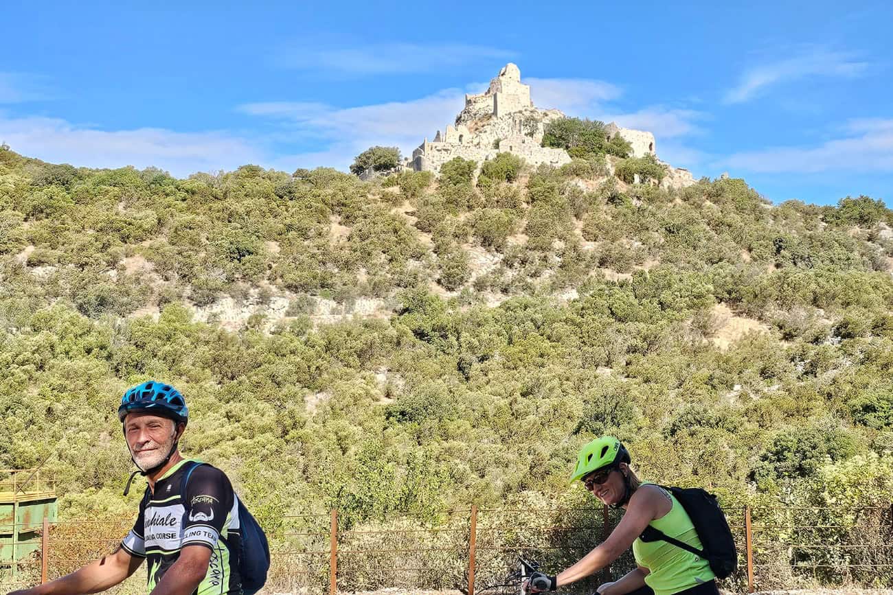 Coppia di ciclisti osserva la Rocca di San Silvestro durante il tour in e-bike da Campiglia a Suvereto