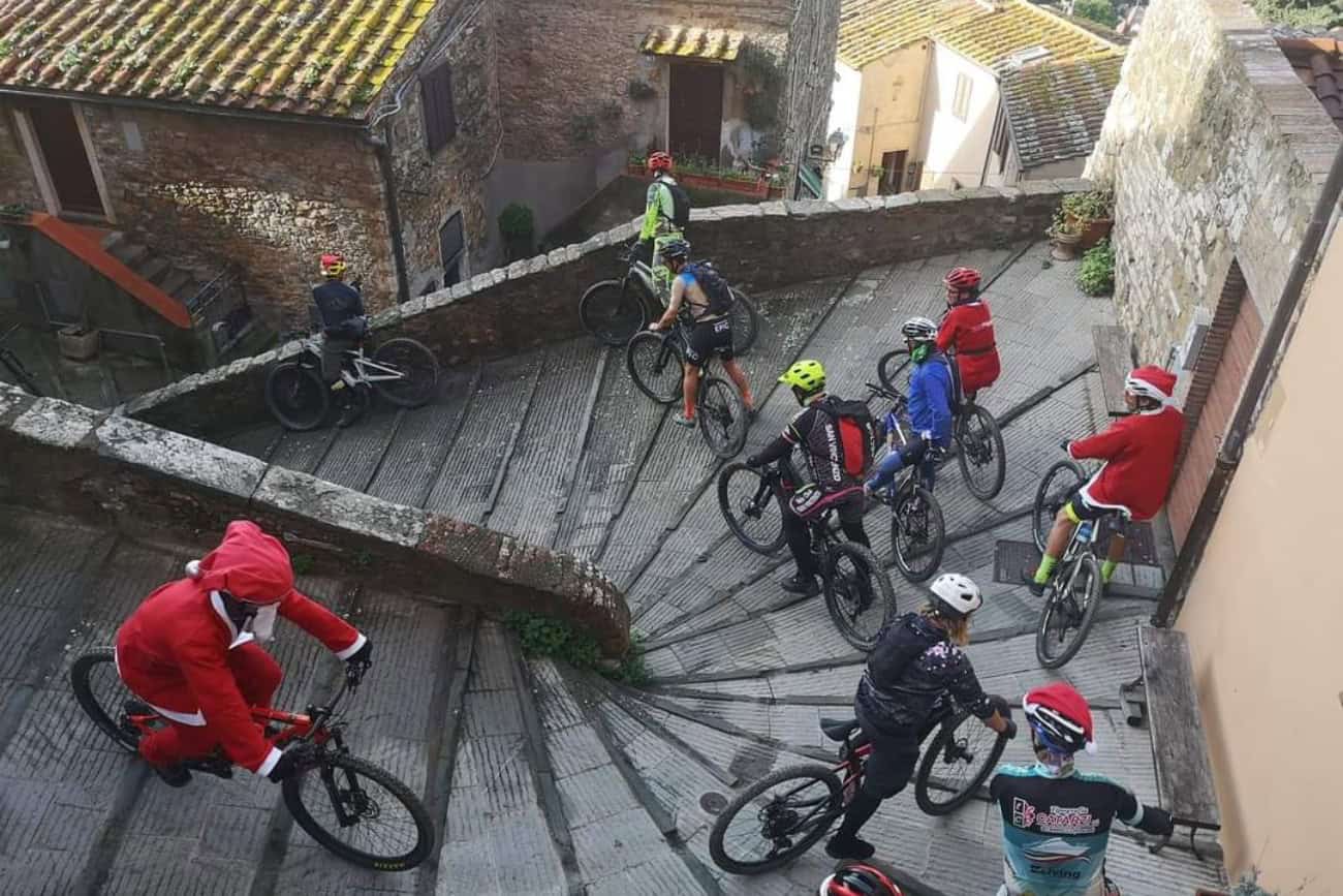 Ciclisti che affrontano una discesa ripida tra le antiche mura di Suvereto