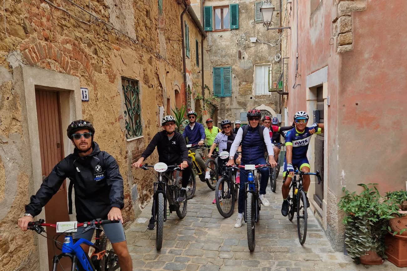 Gruppo di ciclisti che esplora un caratteristico vicolo nel centro storico di Suvereto
