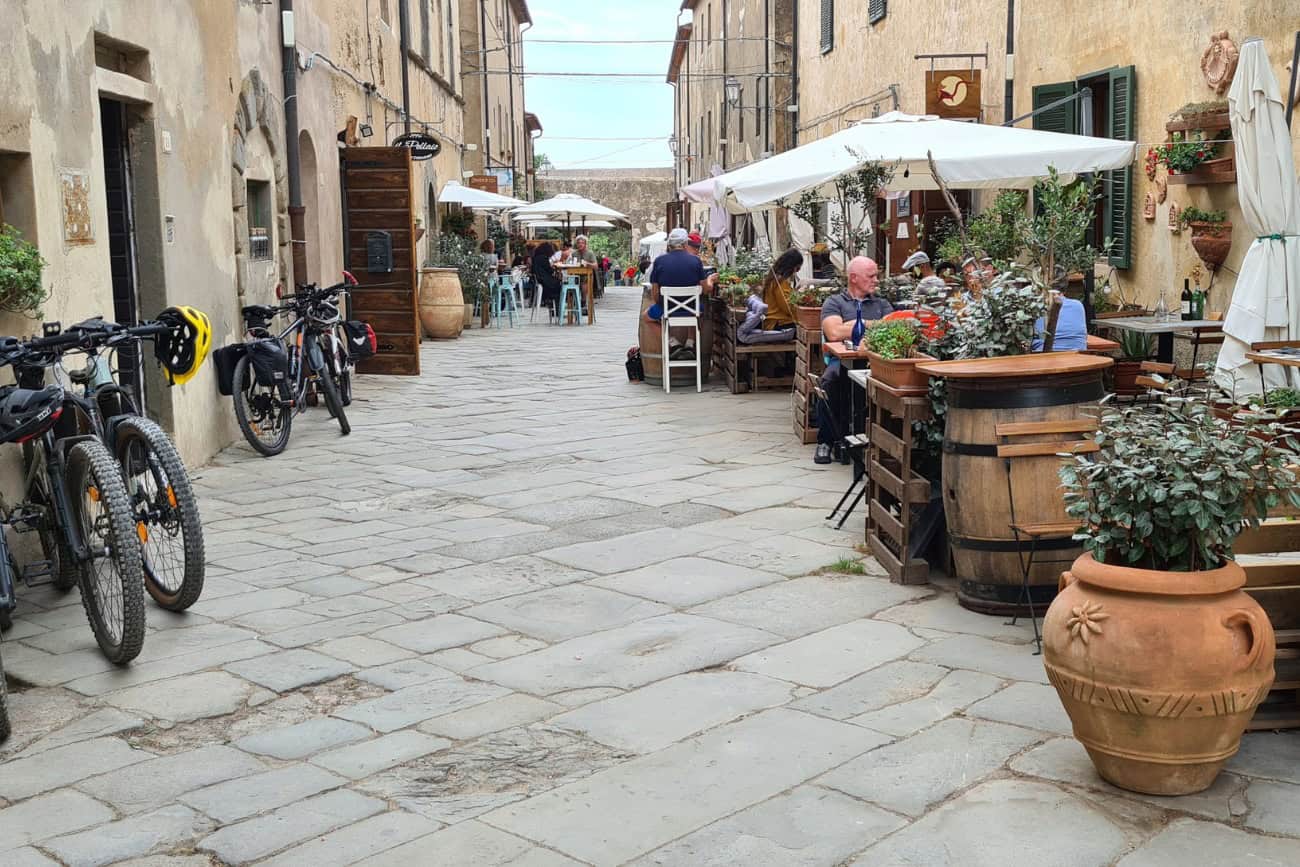 Pittoresca via del centro storico di Suvereto con biciclette parcheggiate e tavolini all'aperto