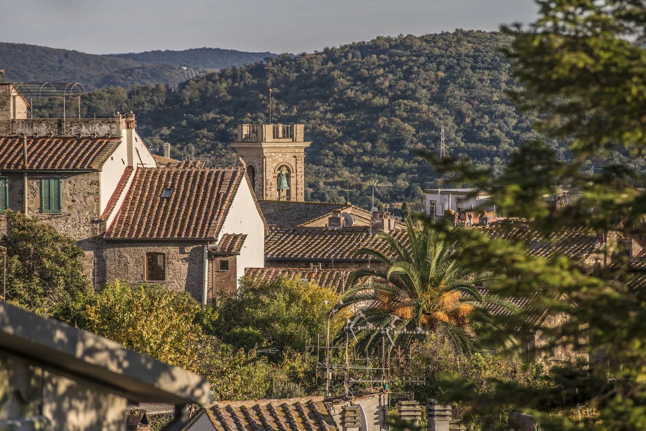 Vista del borgo di Suvereto con i suoi tetti in cotto, la torre campanaria e le colline verdi sullo sfondo, nella campagna toscana