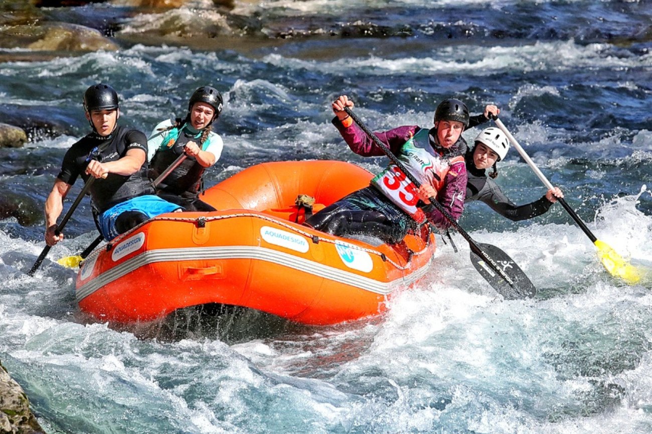 Squadra di Garfagnana Rafting in azione durante una gara fluviale su un gommone arancione